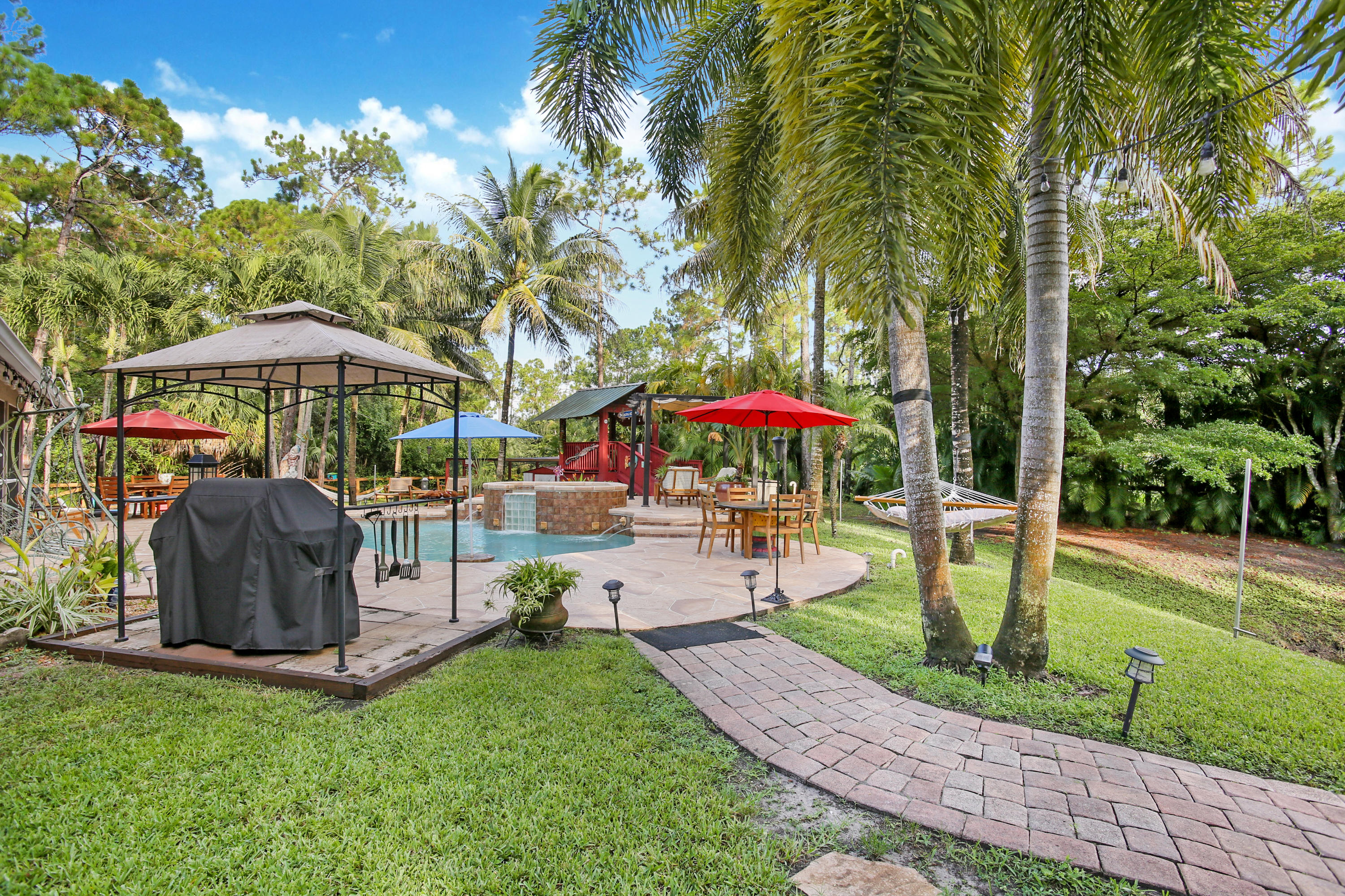 18604 43rd Road North Loxahatchee, FL 33470 - Photo 20 of 40 a view of a swimming pool with a table and chairs under an umbrella