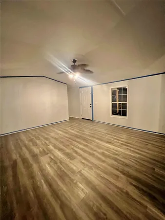 an empty room with wooden floor and fan