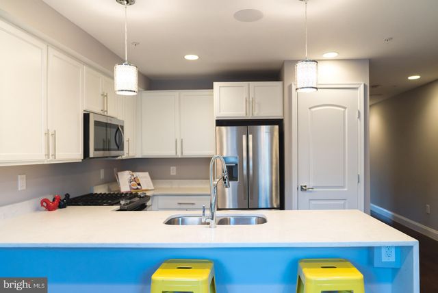 a kitchen with kitchen island granite countertop a sink cabinets and stainless steel appliances