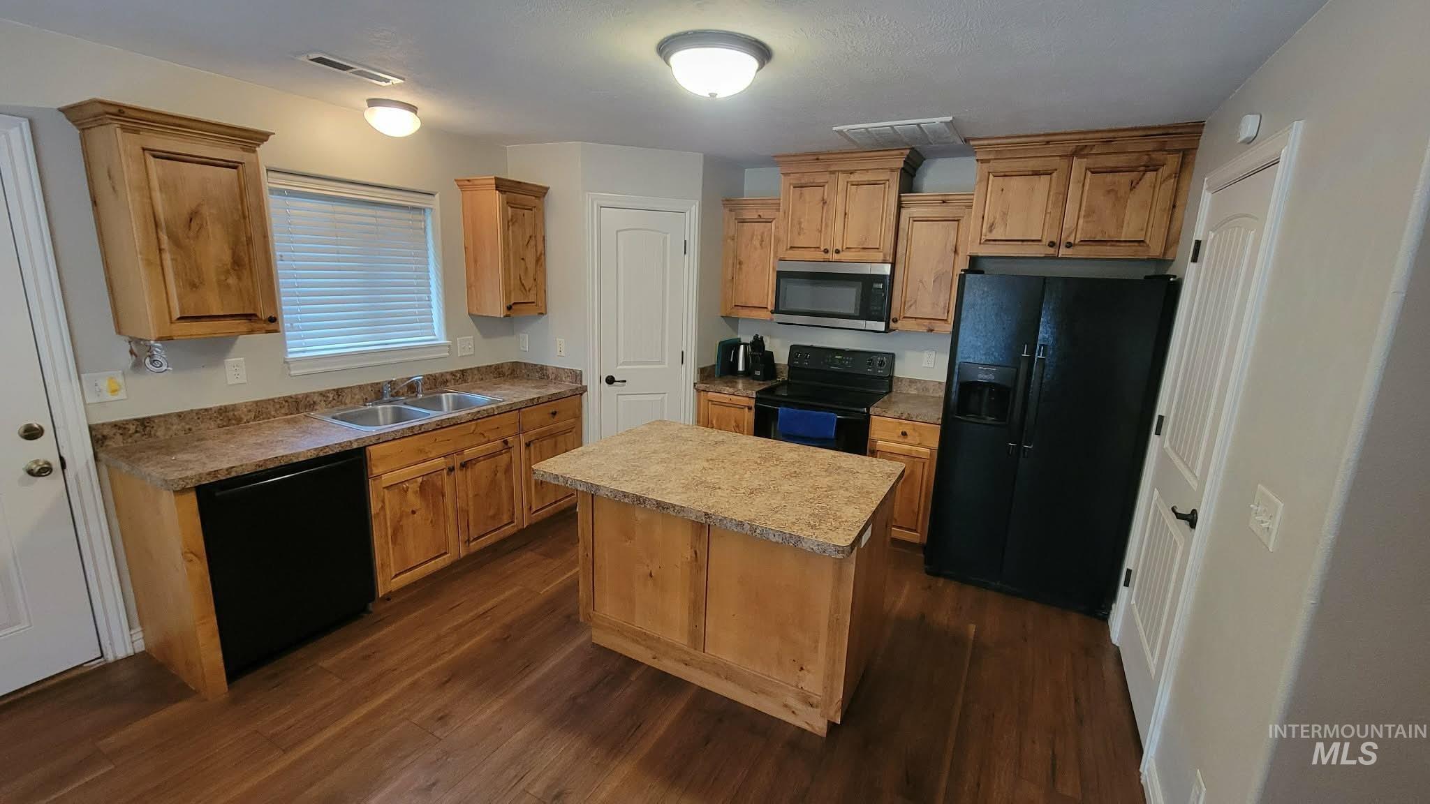 470 Sunflower Road Rexburg, ID 83440 - Photo 3 of 16 Kitchen featuring black appliances, dark wood finished floors, a center island, and light countertops