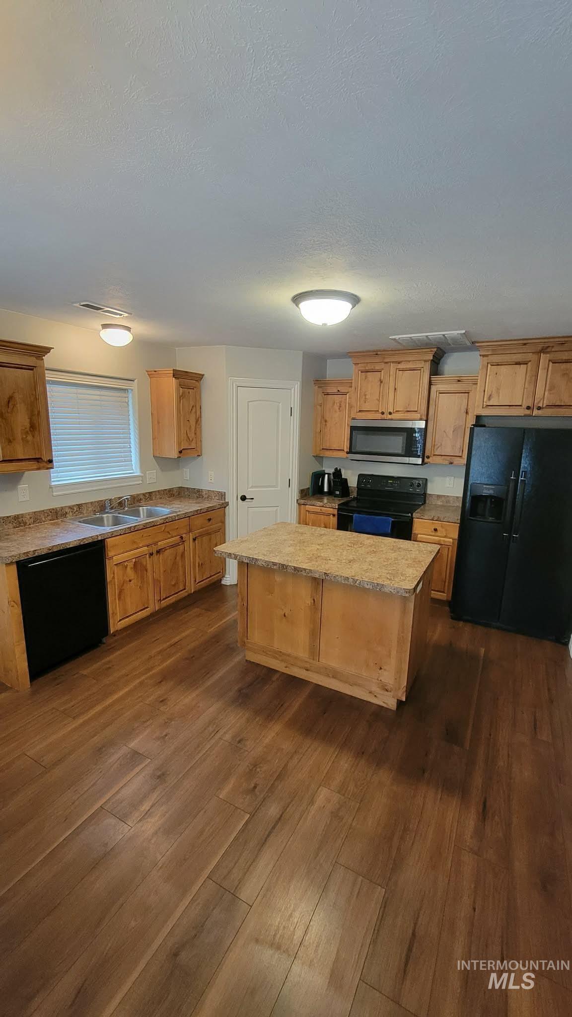 470 Sunflower Road Rexburg, ID 83440 - Photo 4 of 16 Kitchen featuring black appliances, dark wood-type flooring, a kitchen island, and a textured ceiling