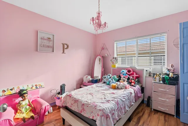 a bedroom with a bed potted plant on the dresser and a window