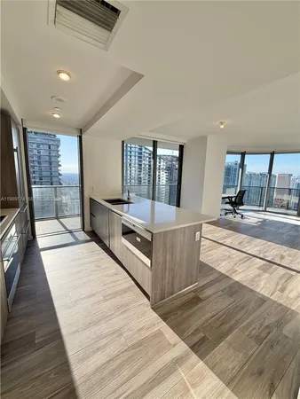 a large white kitchen with stainless steel appliances kitchen island granite countertop a large counter top and white cabinets