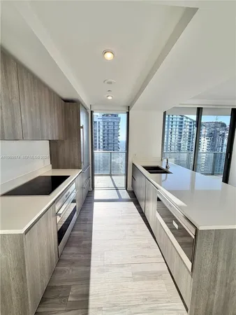 a large kitchen with stainless steel appliances a sink stove and cabinets