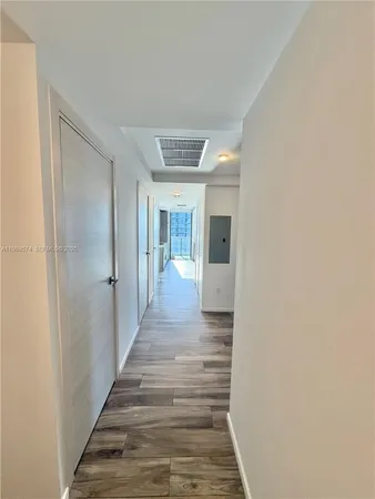 a view of a hallway with wooden floor and a bathroom