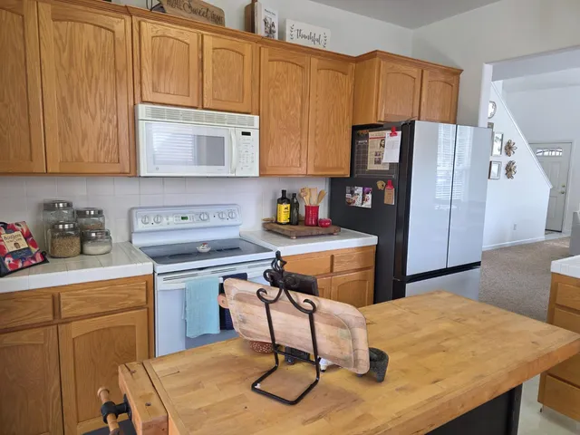 a kitchen with stainless steel appliances granite countertop a refrigerator a sink dishwasher a stove and a refrigerator with wooden floor