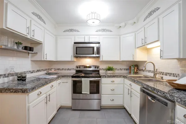 a kitchen with granite countertop white cabinets white stainless steel appliances with a sink and dishwasher