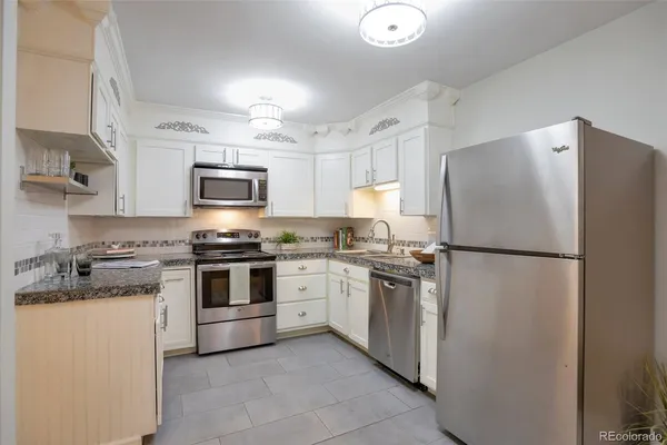 a kitchen with stainless steel appliances granite countertop white refrigerator stove a sink dishwasher and microwave