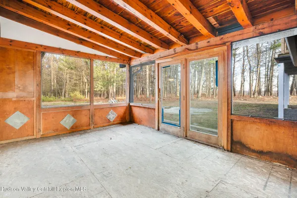 a view of an empty room with wooden floor and windows