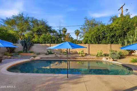 a patio with a table and chairs under an umbrella
