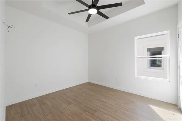 an empty room with wooden floor fan and windows