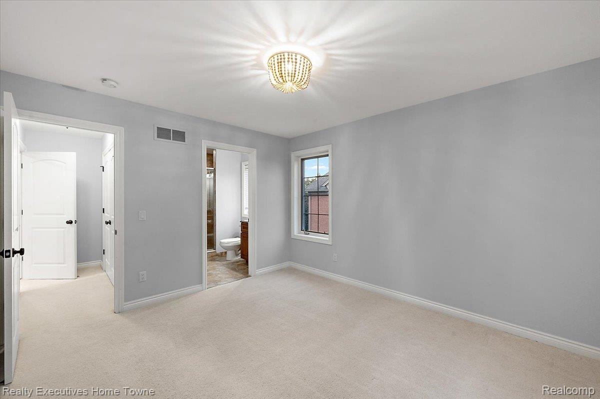 2919 North Addison Circle Rochester, MI 48306 - Photo 32 of 69 Light gray wall paint, off-white carpeting, a decorative beaded chandelier, white trim, and a multi-pane window