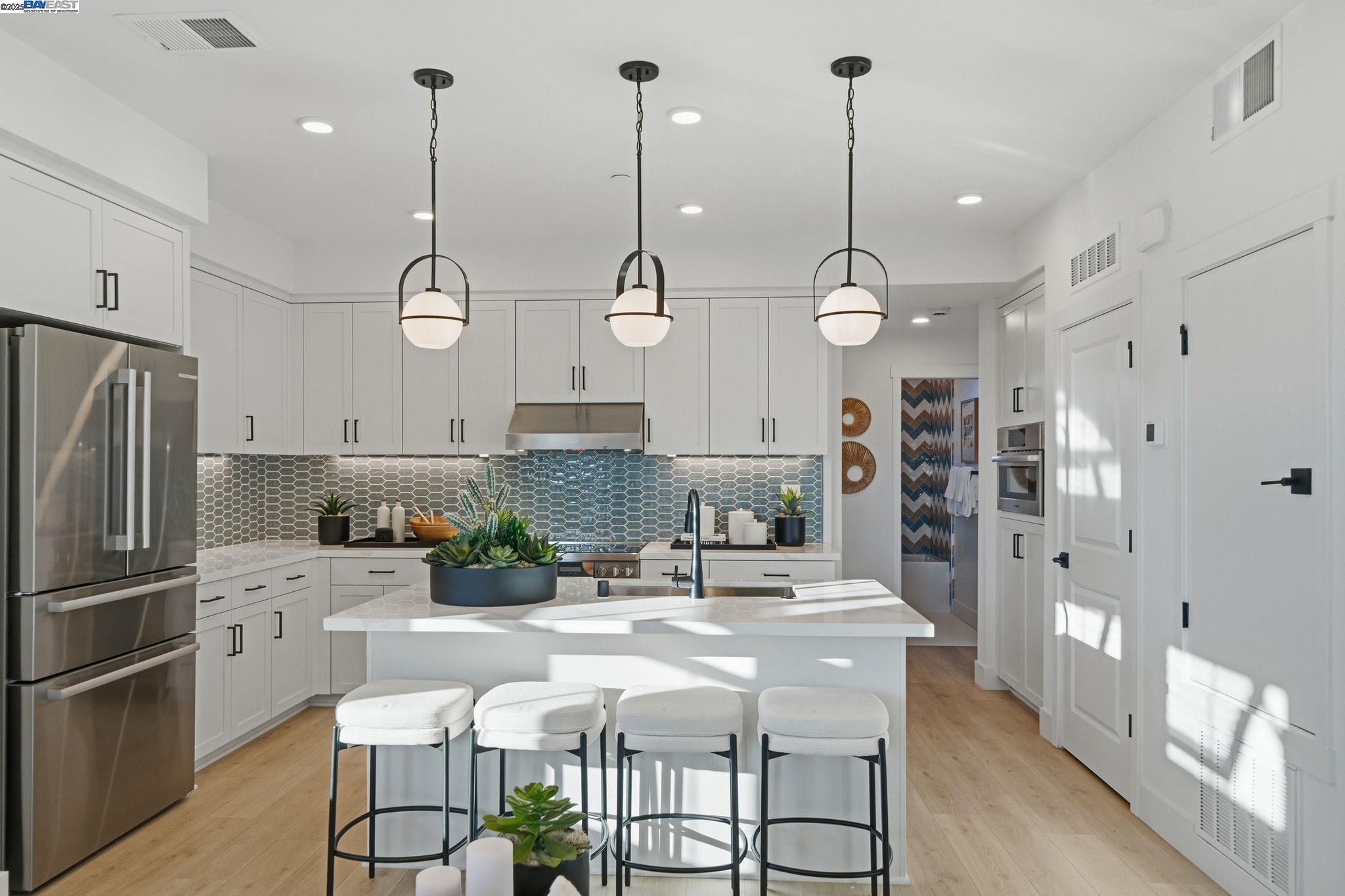 a kitchen with stainless steel appliances kitchen island granite countertop a refrigerator a oven a sink and a chandelier