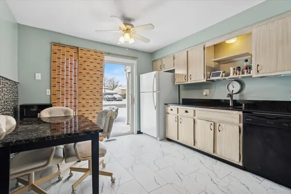 a kitchen with stainless steel appliances granite countertop a stove a refrigerator a sink a dining table and chairs with wooden floor