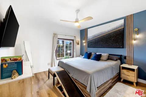 a bedroom with a bed a flat screen tv and a large window with the outer view