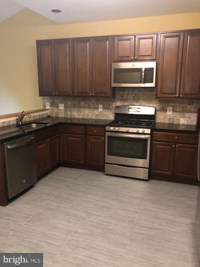 27 Bank Spring Court Owings Mills, MD 21117 - Photo 12 of 27 a kitchen with wooden cabinets stainless steel appliances and a sink