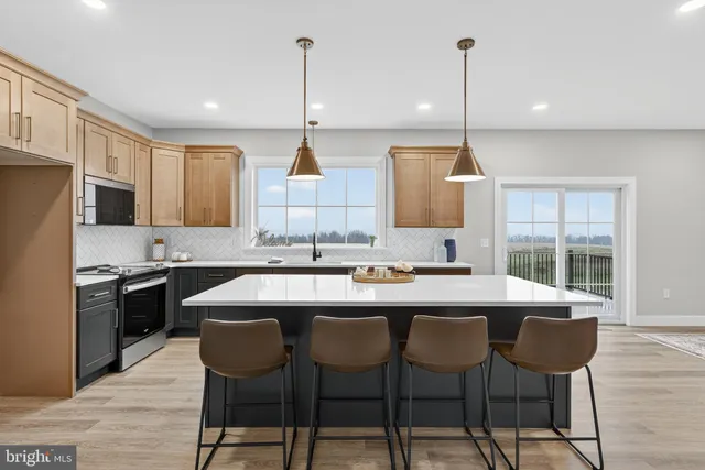 a kitchen with stainless steel appliances granite countertop a stove a sink a kitchen island with chairs and wooden cabinets