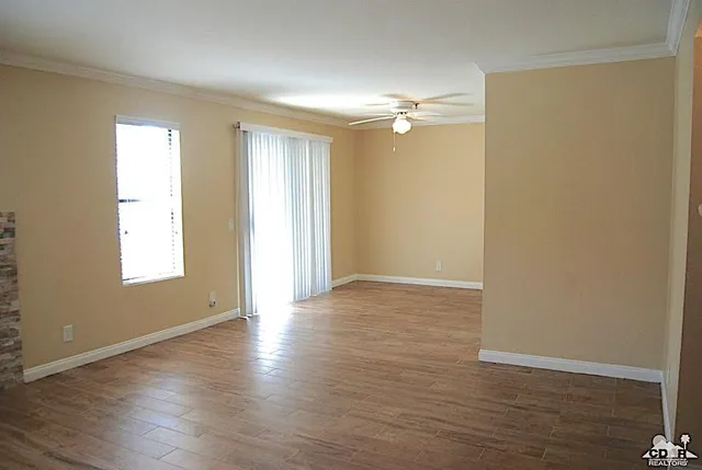 a view of empty room with wooden floor and fan