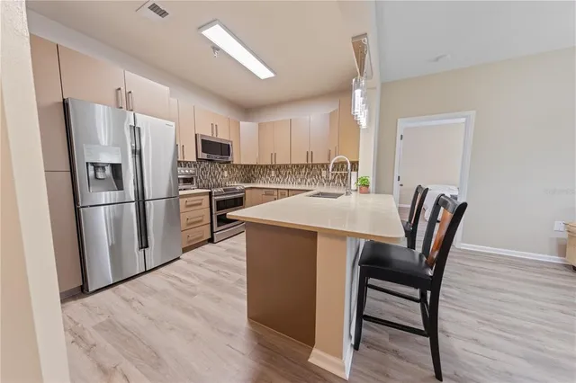 a kitchen with stainless steel appliances granite countertop a dining table chairs refrigerator and a sink