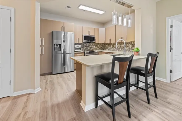 a kitchen with stainless steel appliances a dining table chairs refrigerator and sink