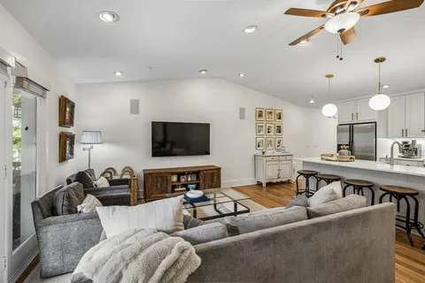 a living room with furniture kitchen view and a flat screen tv