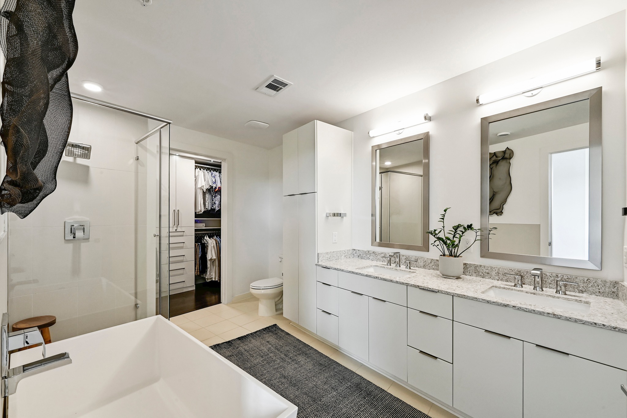 2003 Wilson Street, Unit 1 Austin, TX 78704 - Photo 19 of 40 Primary bathroom with access to walk- in closet. Closet has custom cabinetry designed by California Closets.