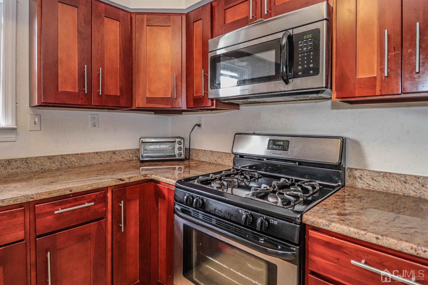 24 Redbud Road Piscataway, NJ 08854 - Photo 6 of 32 a kitchen with wooden cabinets and a stove top oven