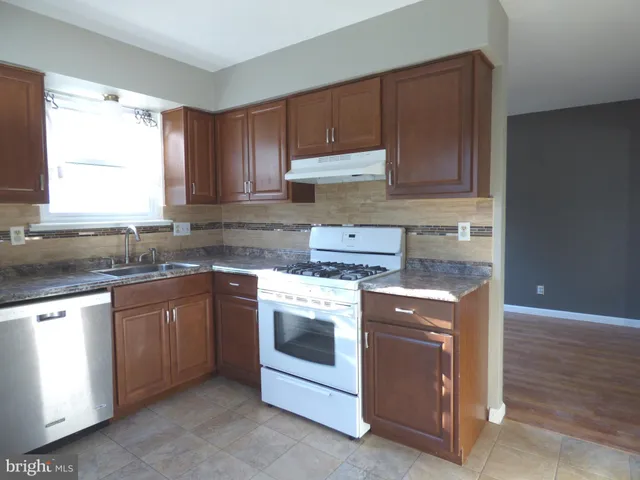 a kitchen with granite countertop wooden cabinets stainless steel appliances and a sink