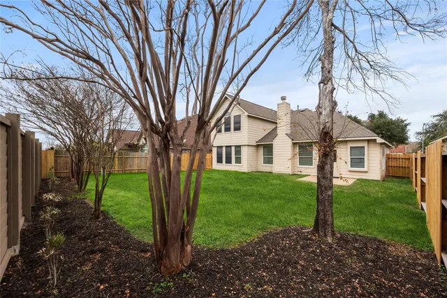 a view of a white house next to a yard with big trees