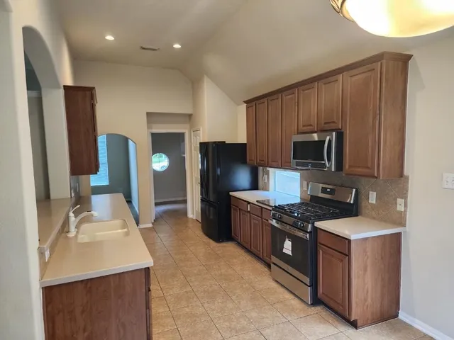 a kitchen with stainless steel appliances granite countertop a sink stove and refrigerator
