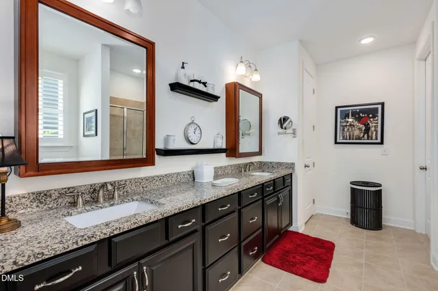 a bathroom with a granite countertop double vanity sink and a mirror