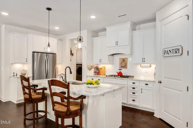 a kitchen with stainless steel appliances a dining table chairs stove and sink