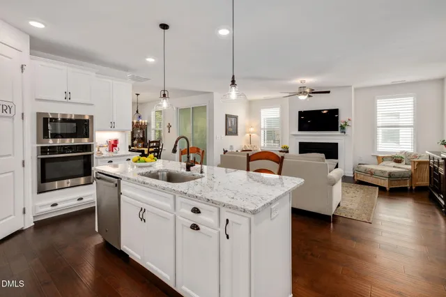 a kitchen with stainless steel appliances kitchen island granite countertop a sink dishwasher a stove and a refrigerator with wooden floor