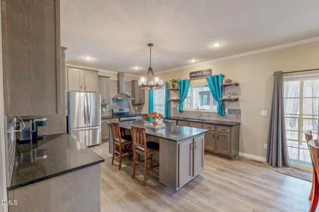 a living room with stainless steel appliances dining table furniture wooden floor and a kitchen view