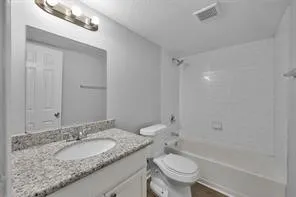 a bathroom with a granite countertop sink a toilet and a bathtub