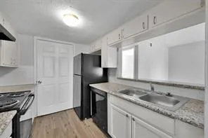a kitchen with granite countertop a sink stove and refrigerator
