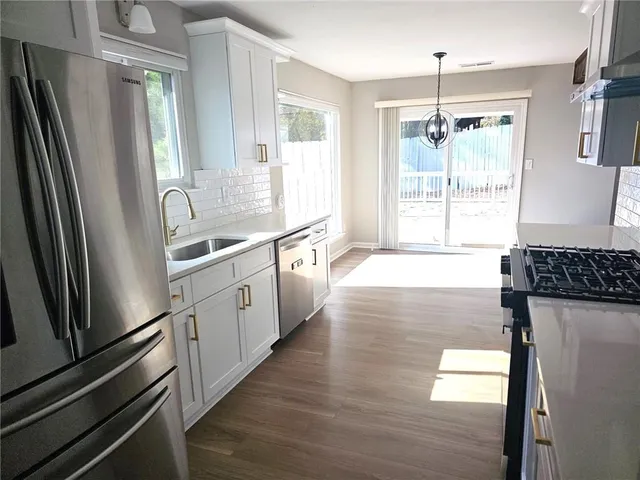 a kitchen with granite countertop a refrigerator a sink a stove and cabinets