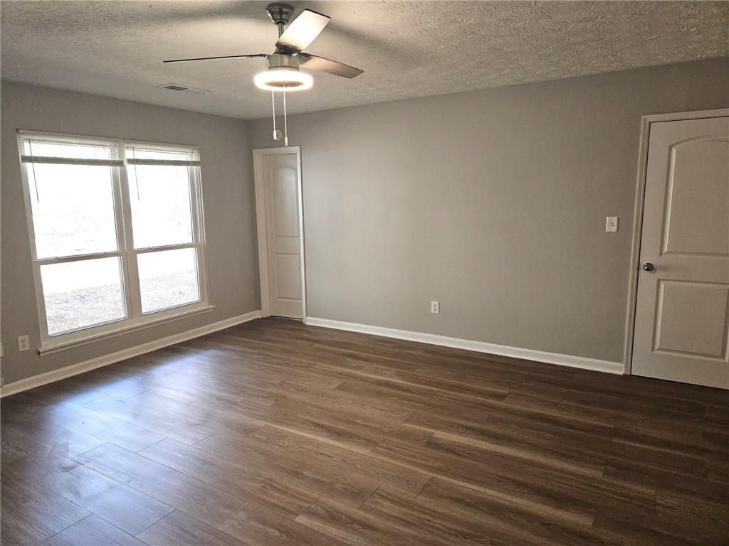 10085 Old Woodland Entry Johns Creek, GA 30022 - Photo 18 of 34 an empty room with wooden floor chandelier fan and windows