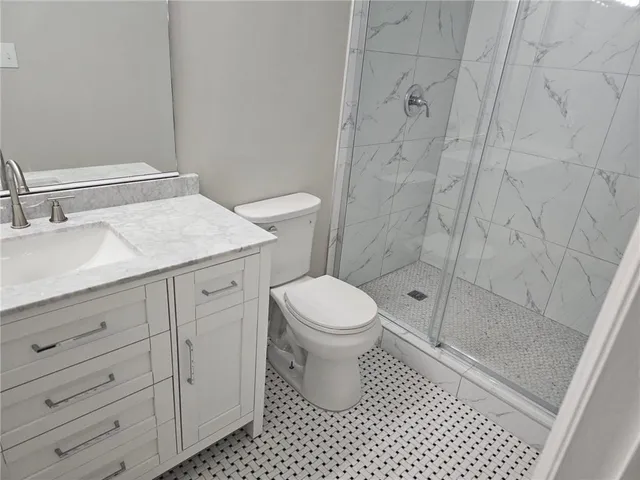 a bathroom with a granite countertop sink toilet and shower