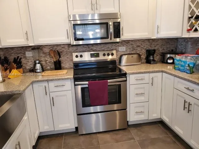 a kitchen with white cabinets and appliances