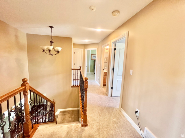 369 Culross Circle Tooele, UT 84074 - Photo 28 of 54 Carpeted landing featuring a chandelier light fixture, wood-finish handrail, and wrought-iron balusters
