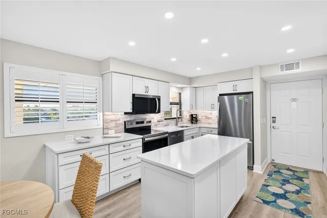 a view of a kitchen with cabinets stainless steel appliances and a window