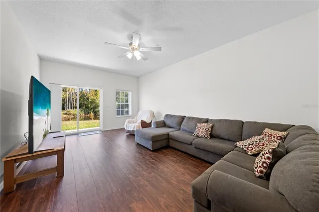 an empty room with wooden floor chandelier fan and windows