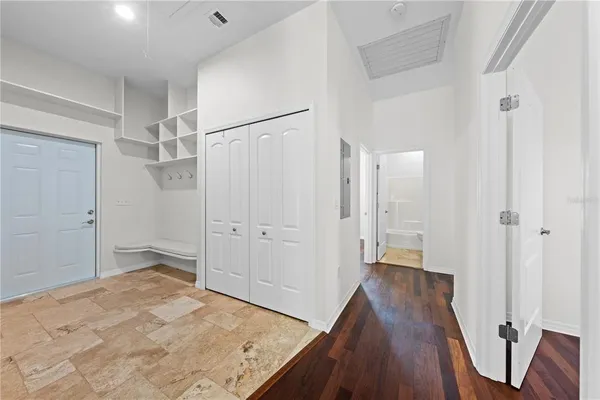 an empty room with wooden floor chandelier and windows