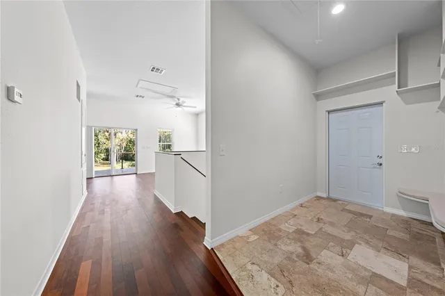 a view of a livingroom with wooden floor a ceiling fan and staircase
