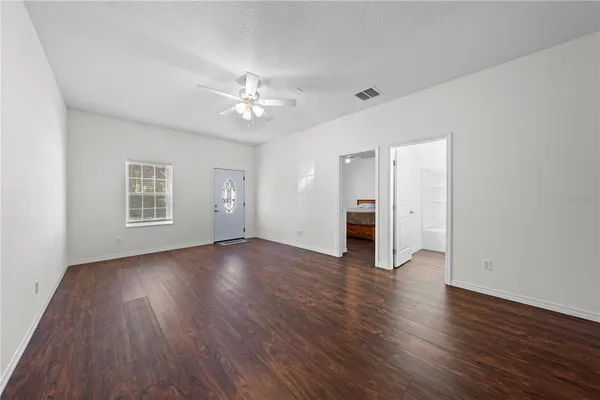 a view of an empty room with wooden floor and a ceiling fan