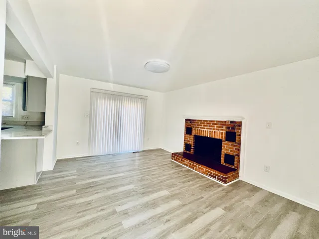 a view of an empty room with a fireplace and a window