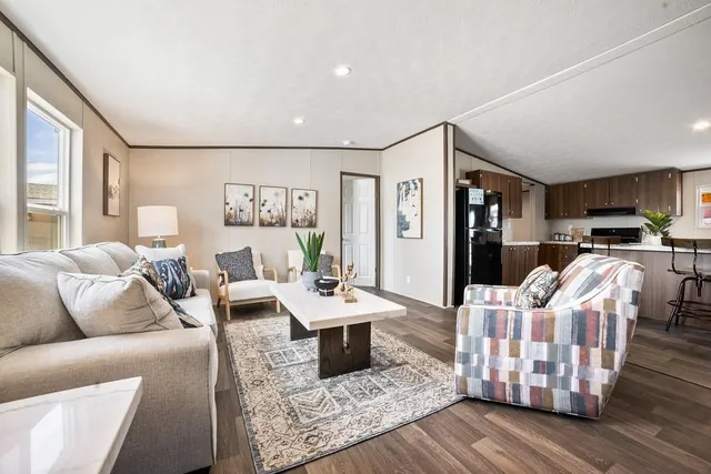 a living room with furniture kitchen view and a large window