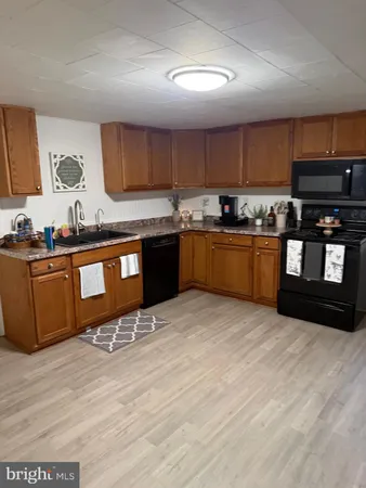 a large kitchen with stainless steel appliances granite countertop a stove a sink dishwasher and a microwave oven with wooden floor