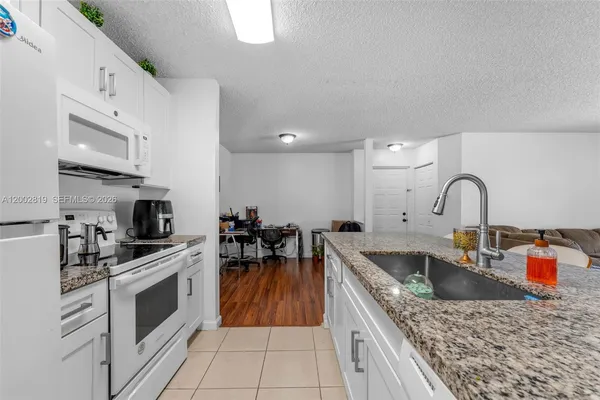 a kitchen with granite countertop a sink a counter top space appliances and cabinets